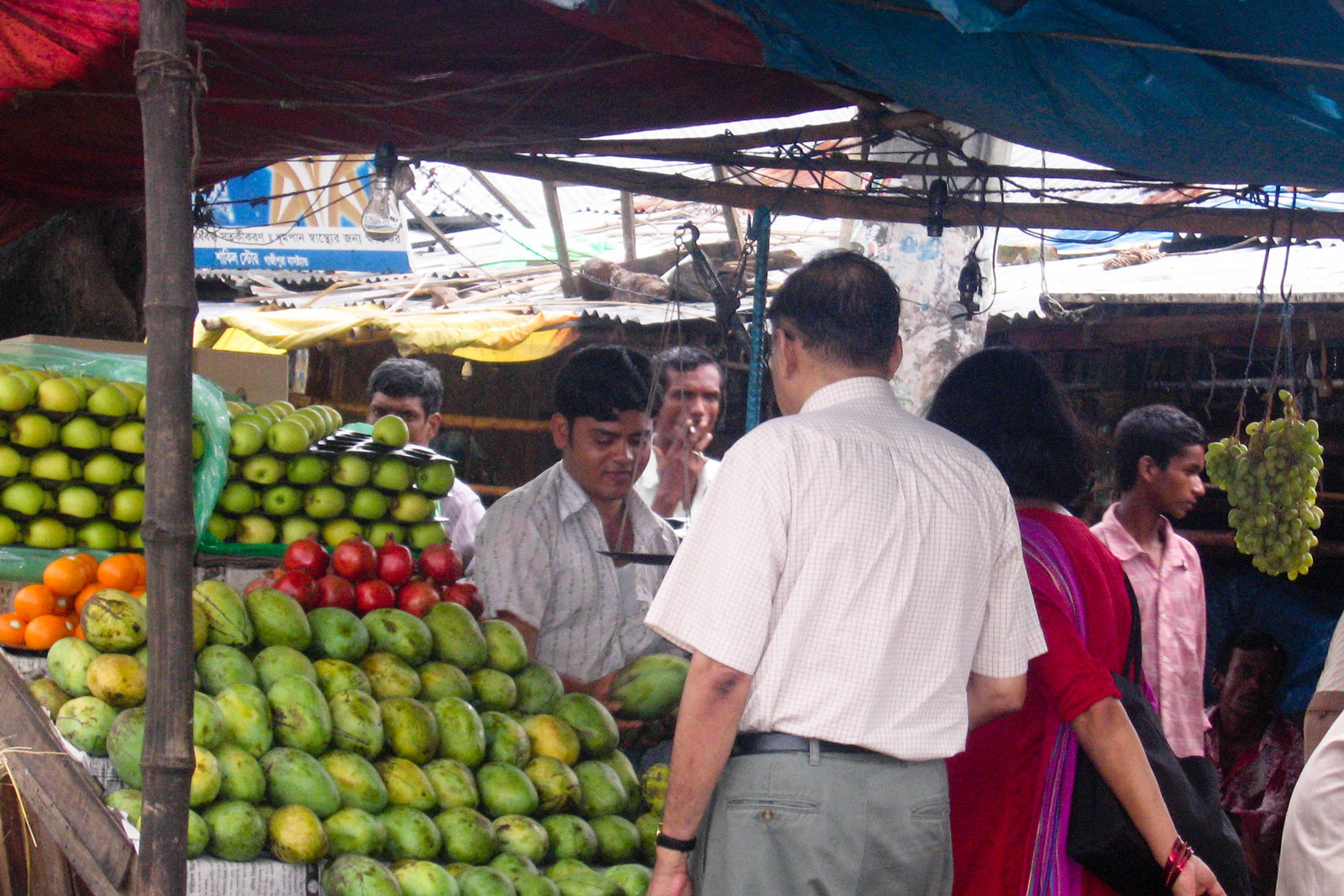 My dad and mom buying mangoes at an open-air market in Bangladesh.