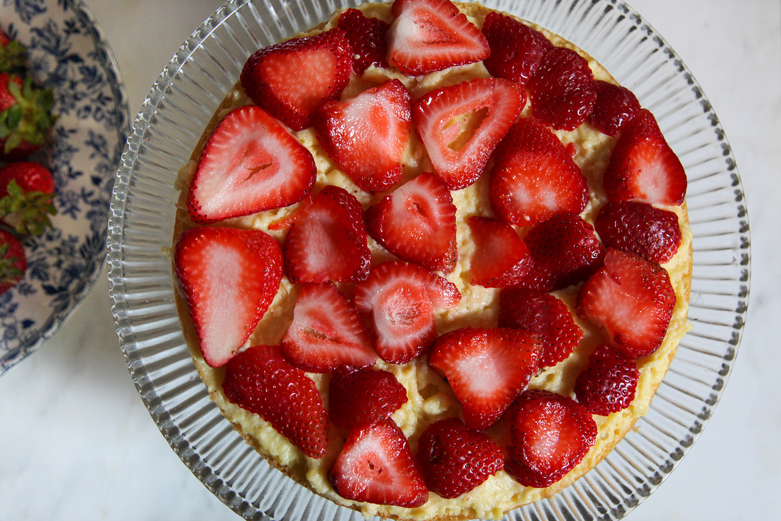 Sliced strawberries on custard cream on lower layer for strawberry cake