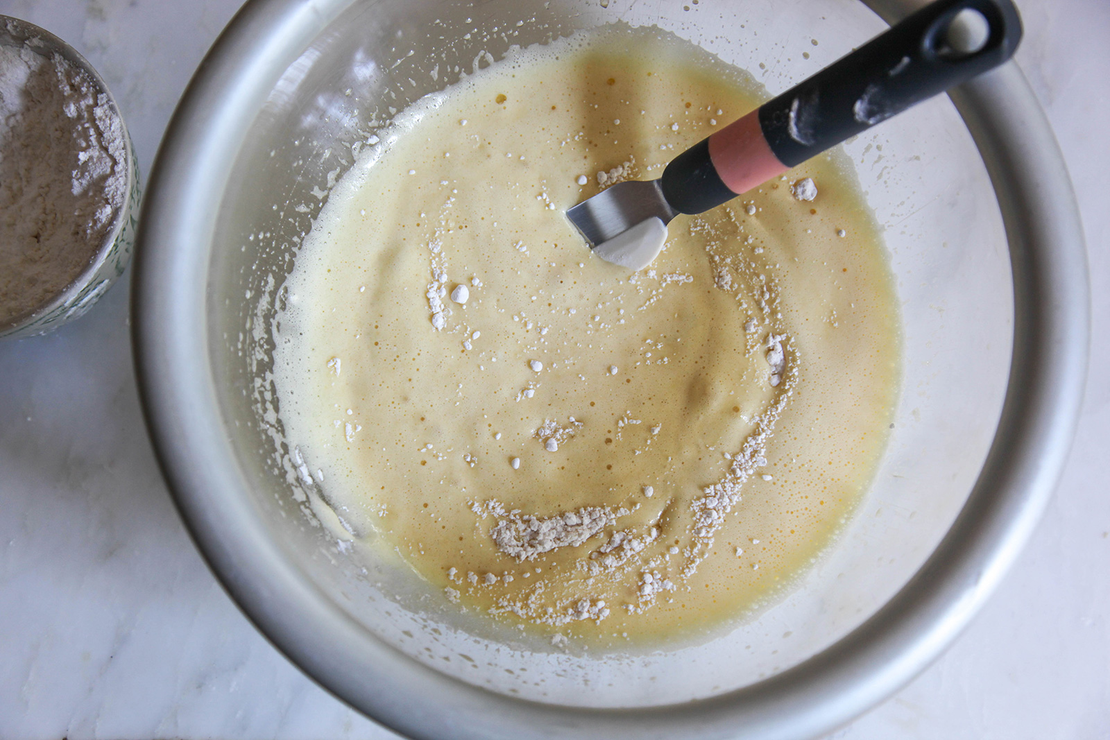 Folding in flour mix to make cake batter, for baking strawberry cake