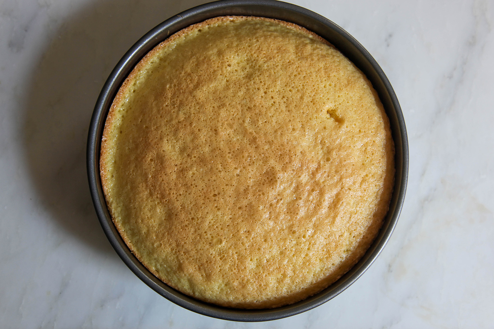 Baked cake in pan, ready to remove and cool, in prep for strawberry cake