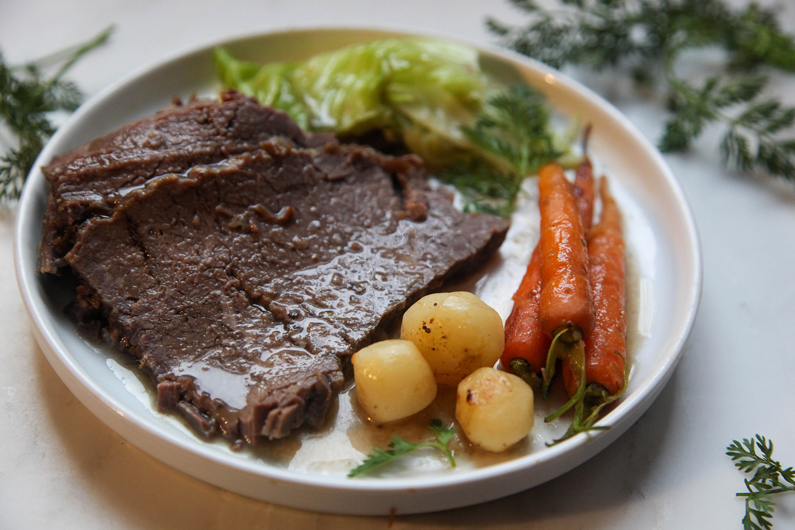 Corned Beef after 3.5 hours of cooking, set on a plate with carrots and potatoes