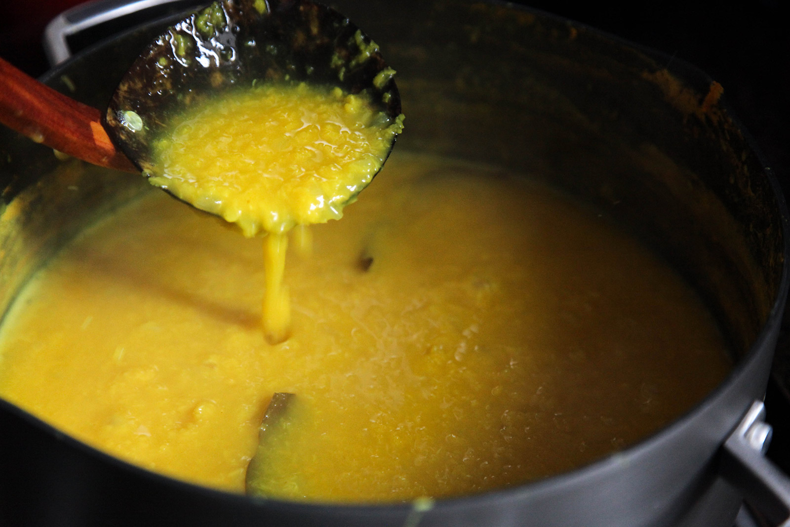 Consistency of Cooked Golden Yellow Dal (Lentil Soup) with Turmeric, Garlic, Cilantro.