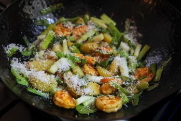 previously sautéed shrimp added back to wok with green garlic & sprinkled with grated coconut
