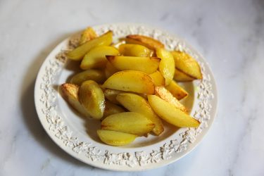 lightly fried potatoes set aside on a plate, to be used for green garlic dish