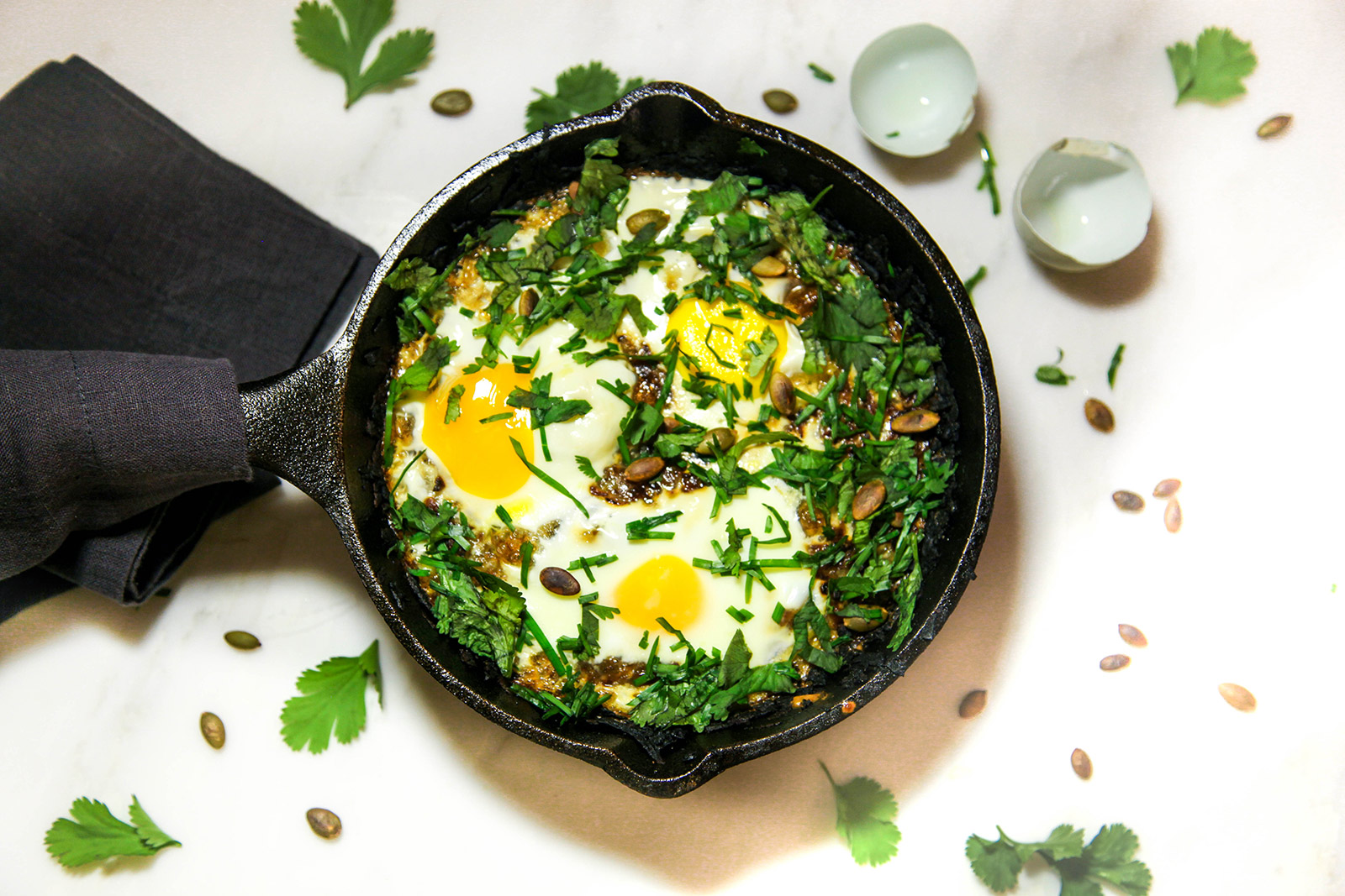 Crispy Potato Cake Nestled with Soft Baked Gooey Eggs, topped with Fresh Chives and Toasted Pumpkin Seeds