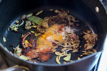 Powdered spices added to sautéed ingredients in pot