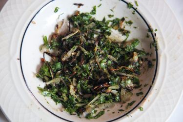 Charred chilies, garlic cloves, raw shallots, sauteed shallots, and chopped cilantro smashed together on a plate