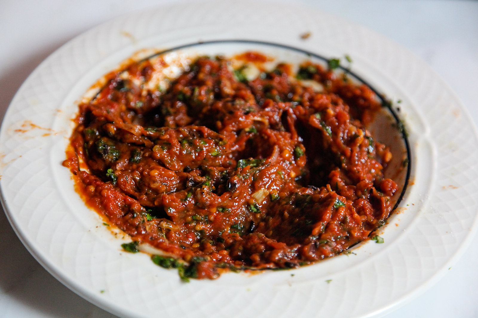 Cooked tomatoes mixed with smashed charred and fresh ingredients on a plate