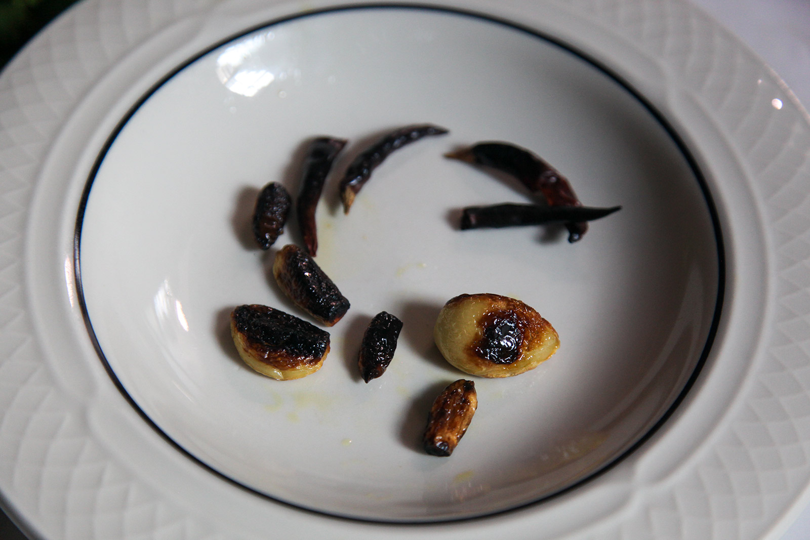 Charred dried red chilies and garlic cloves cooling on a plate